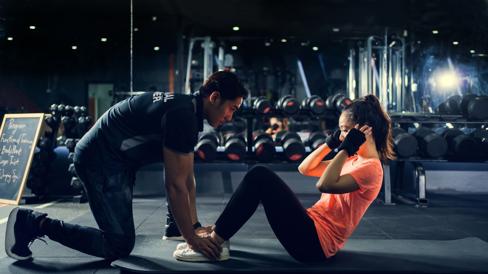 Personal Trainer zum Üben von Sit-ups im Fitnessstudio