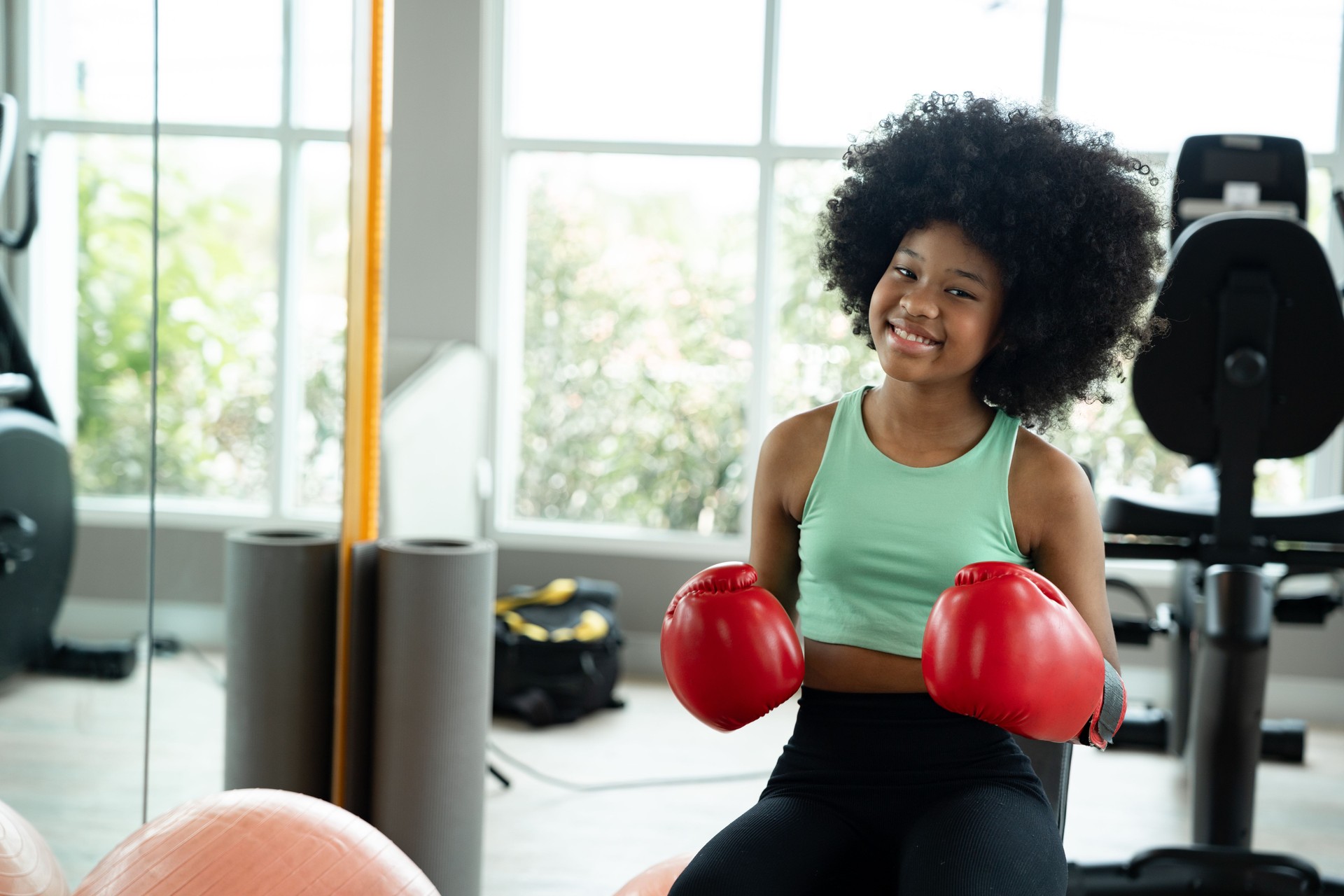 Porträt Afroamerikanisches Mädchen mit roten Boxhandschuhen im Fitnessstudio