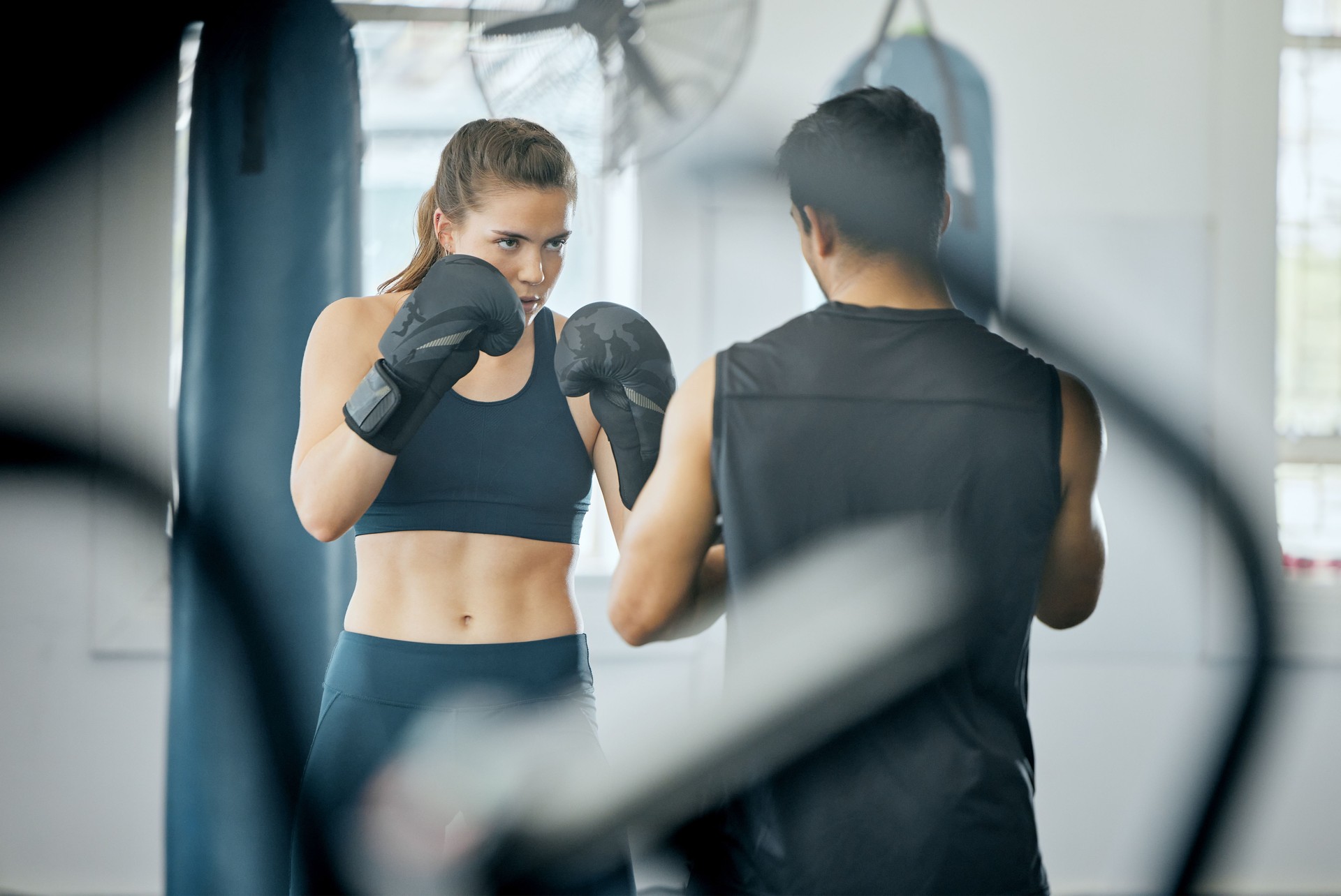 Box-Fitness-Training mit Trainer im Fitnessstudio, wütende Frau lernt Selbstverteidigung mit Trainer und lernt Cardio-Training für Wellness im Sportverein. Männlicher Instruktor, der Workout-Kurs im Zentrum unterrichtet