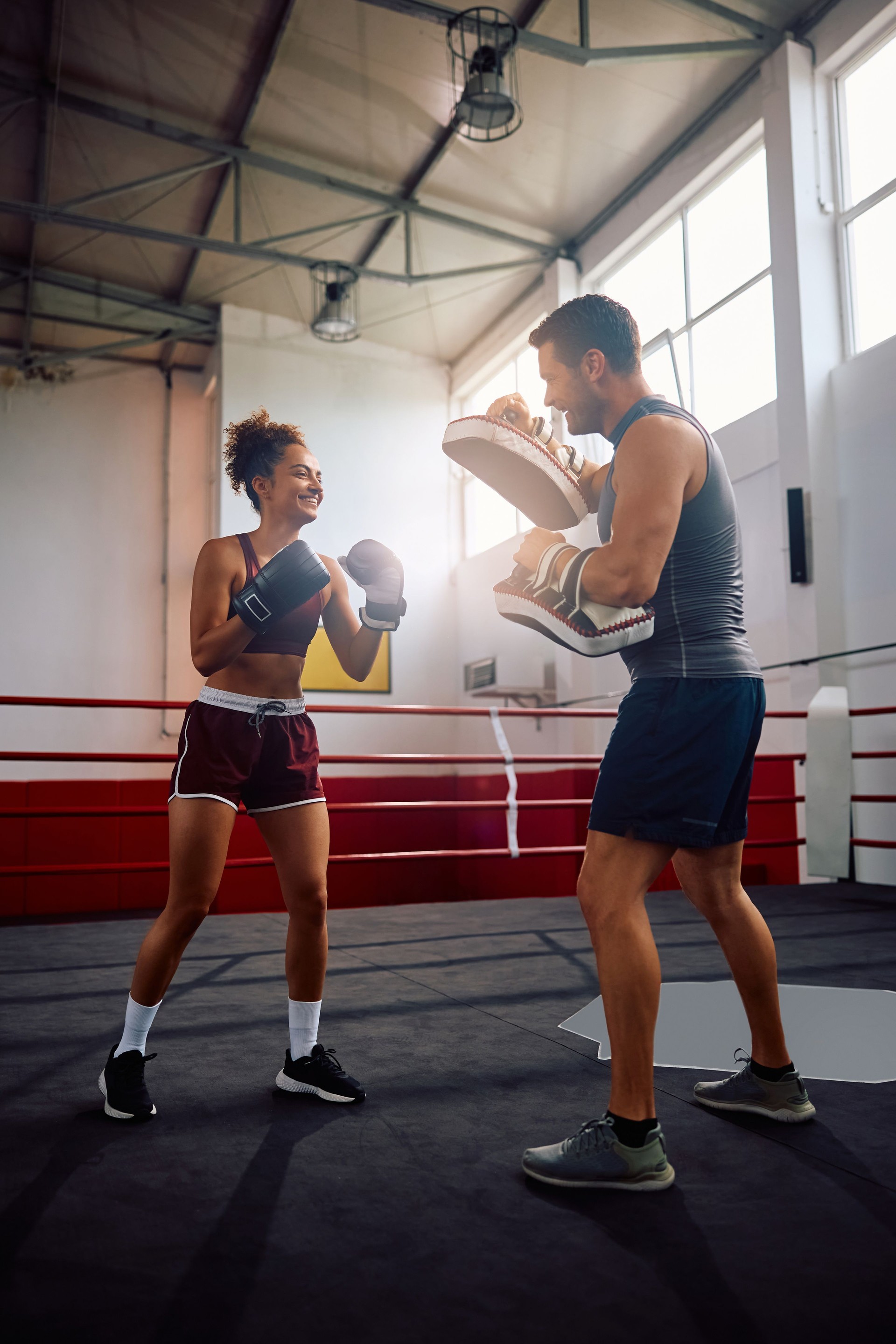 Kämpferin beim Boxen mit ihrem Trainer im Fitnessstudio.